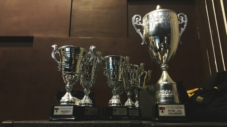 several silver and gold trophies on wooden surface